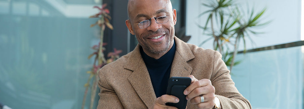 Man wearing Readers while looking at his phone