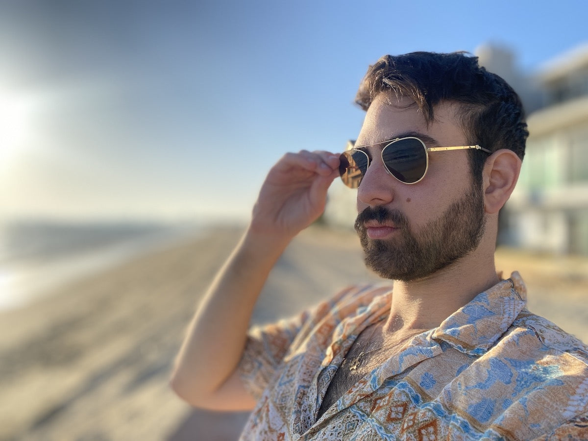 Man sitting on a beach wearing ThinOptics Mountain View Sunglasses.