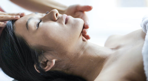 Woman with her eyes closed lying down while someone touches her face