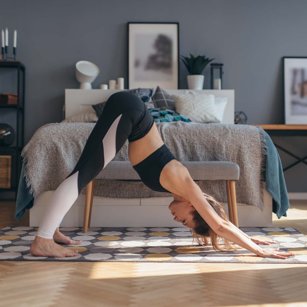 woman in bedroom doing yoga downward facing dog pose Adho Mukha Svanasana