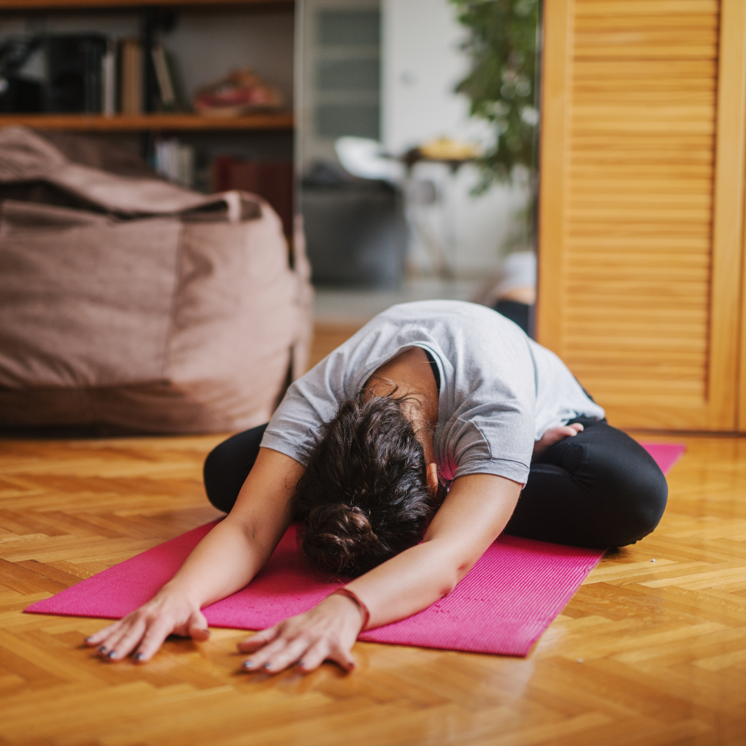 woman in living room doing yoga child's pose Balasana