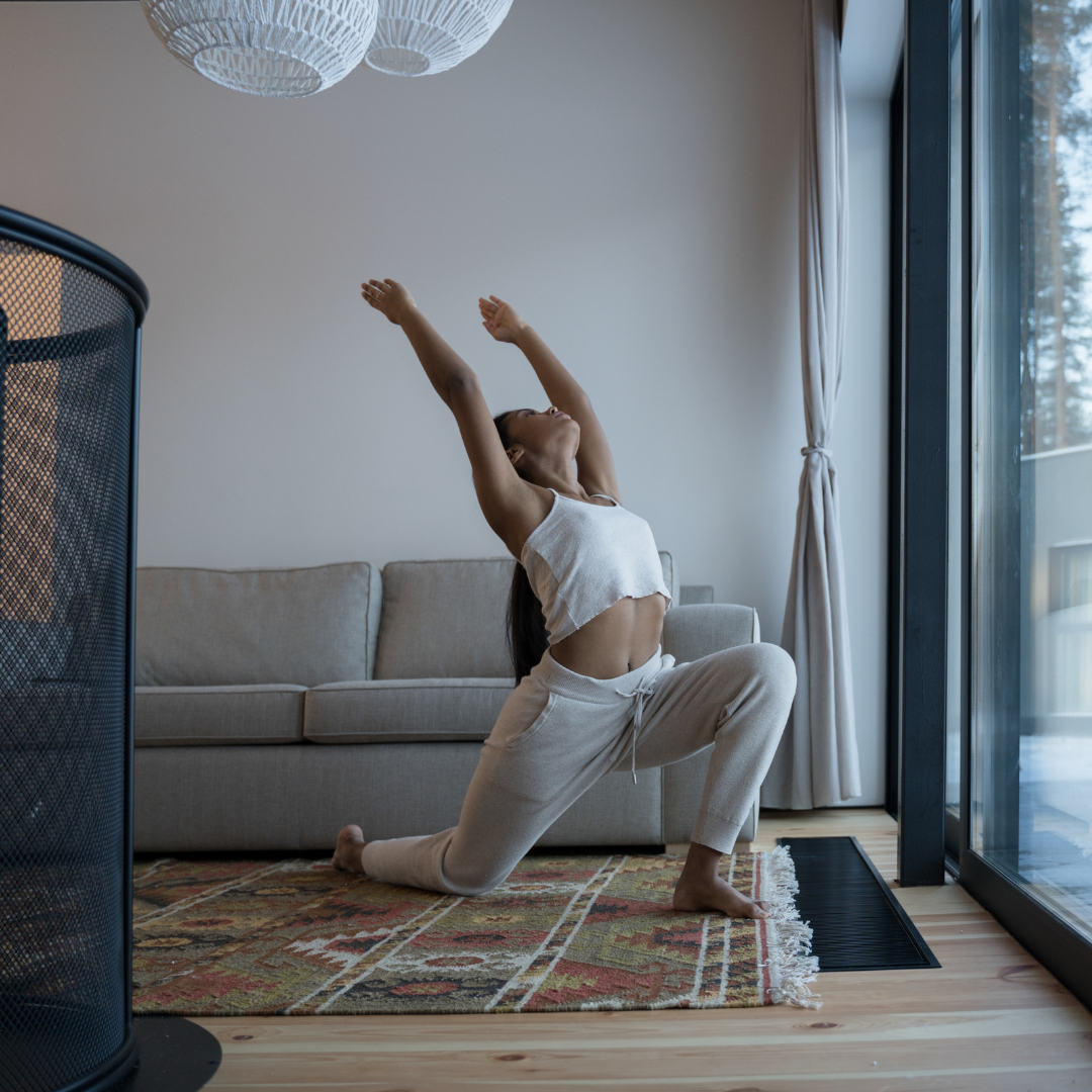 woman in living room doing yoga warrior 1 pose Virabhadrasana