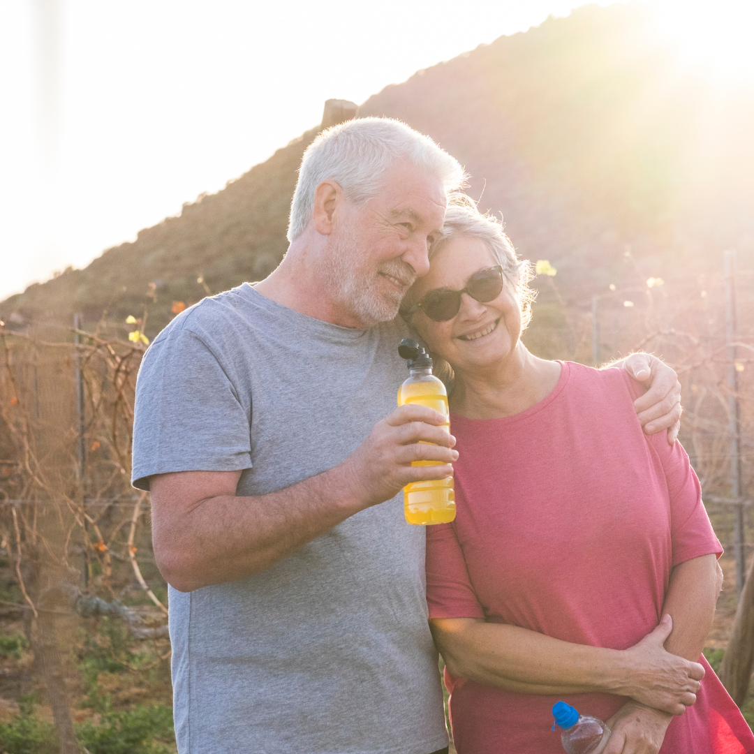 happy elderly couple enjoy a walk through the park and sip from a water bottle