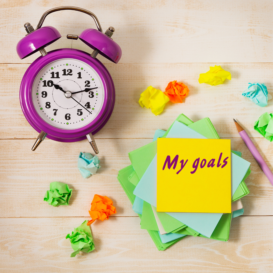 clock and sticky note on table that says my goals