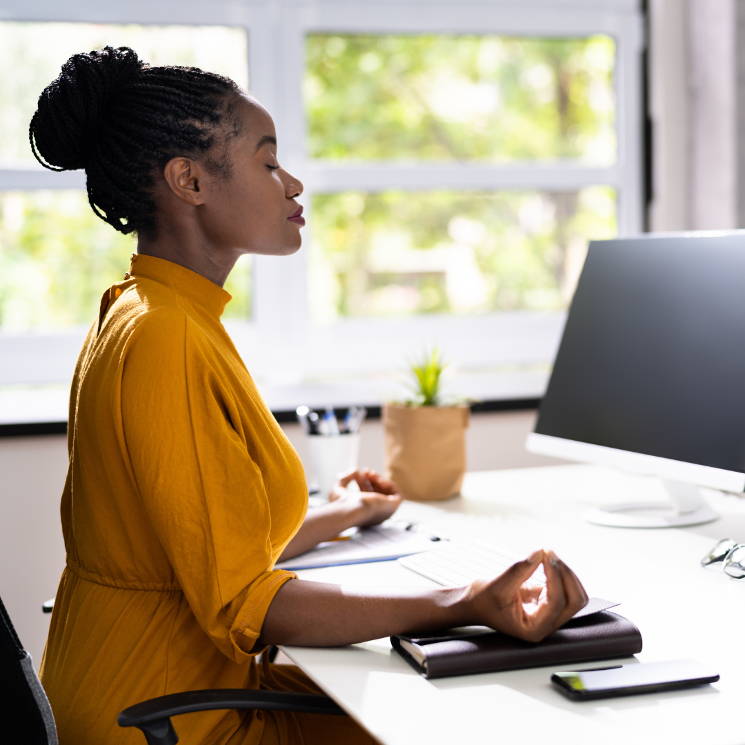 woman at work desk pausing to meditate
