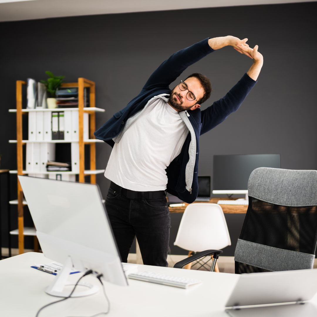 man in office standing up and stretching his arms