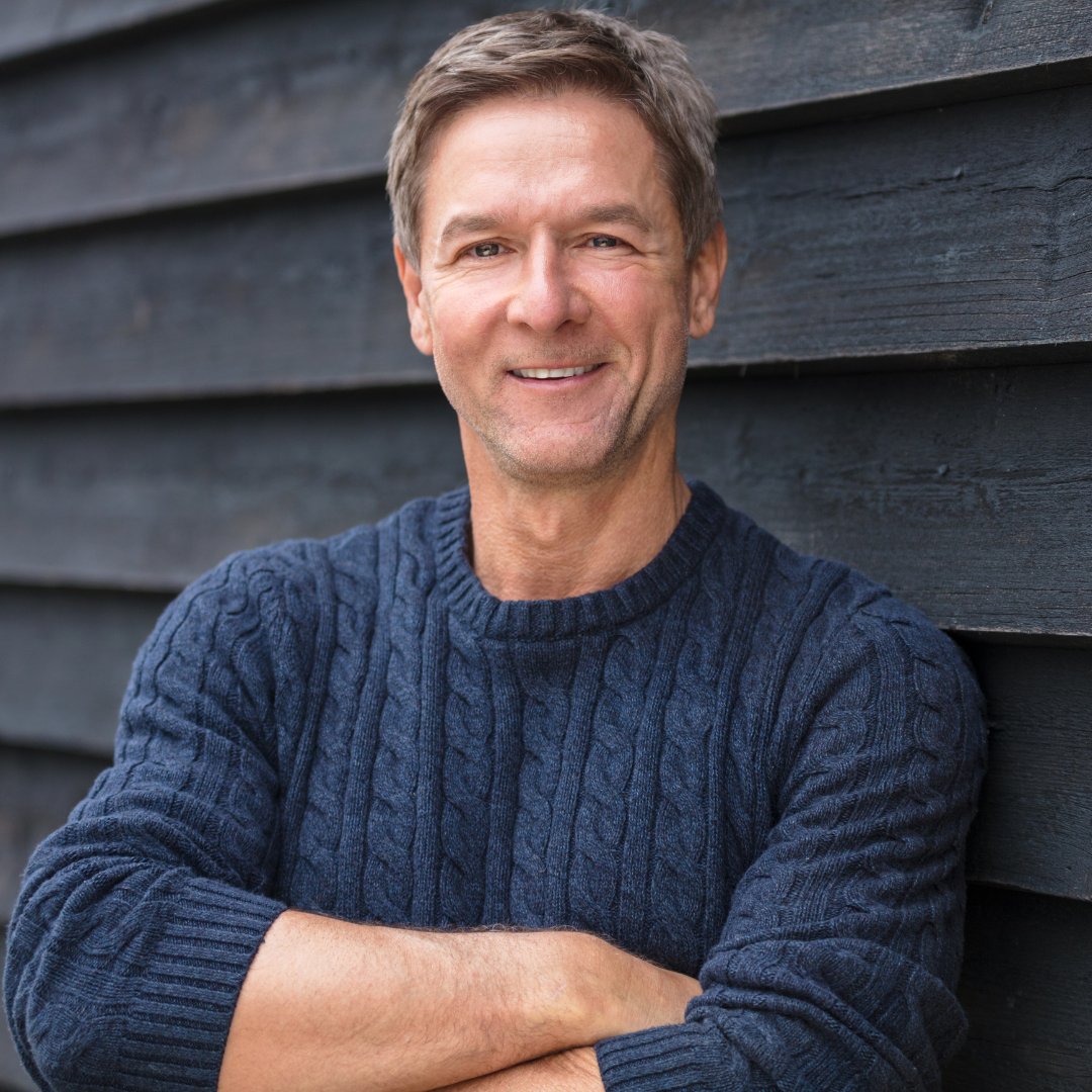 man standing outside with his arms crossed against a wall