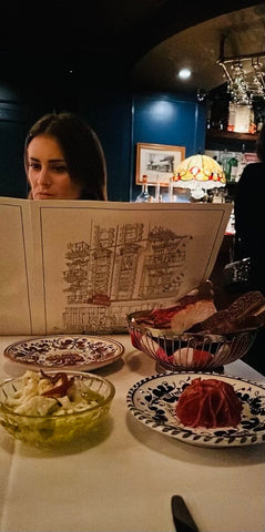 Erica Bethe Levin reading restaurant menu with Italian food in front of her