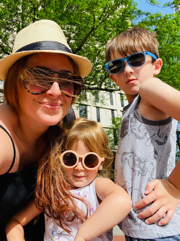 Mom with sunglasses and a sunhat with two young children in sunglasses