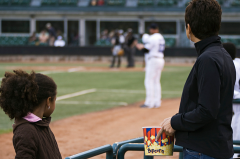 Mom and daughter as spectators watching a baseball game with popcorn