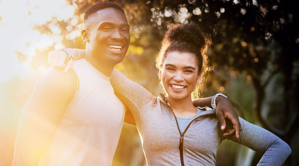 Smiling man and woman in workout clothes outdoors.
