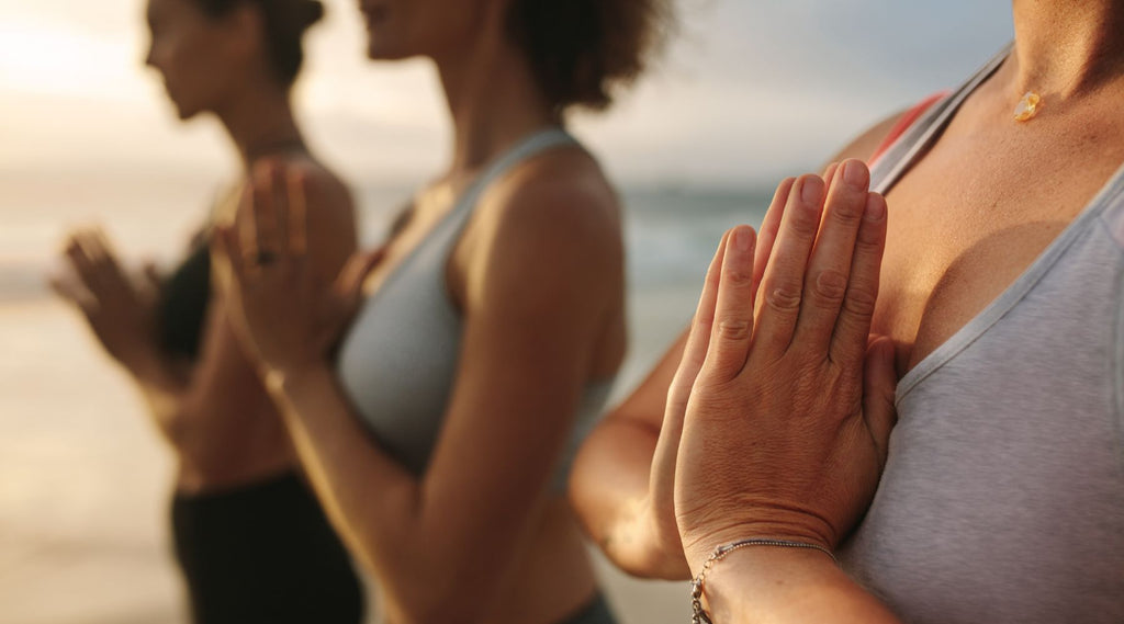 Women practicing yoga at sunset on the beach.