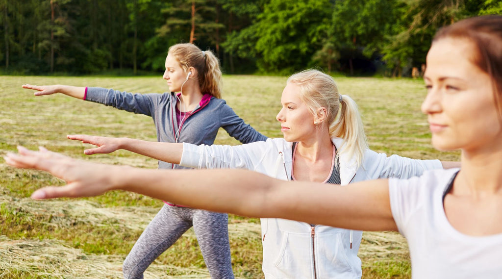 Women practicing Tai Chi outdoors in a grassy field