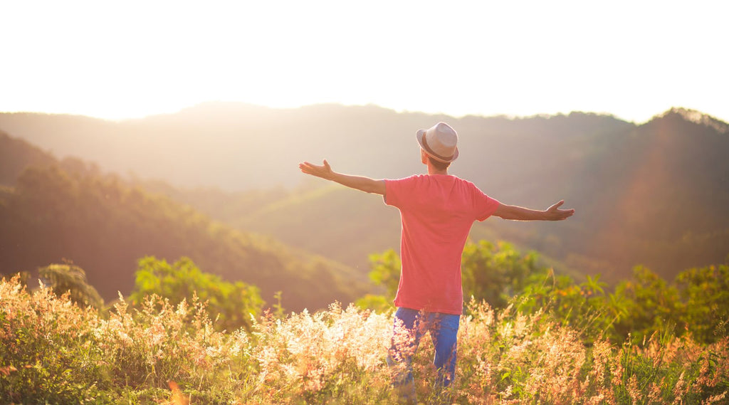 Man with arms wide open enjoying the sunset in a mountainous landscape