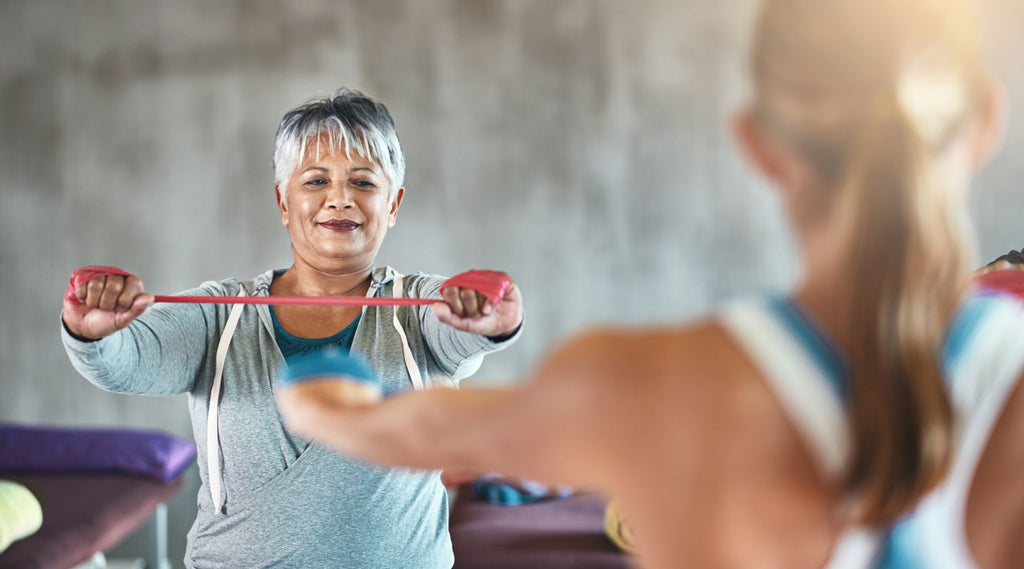 Older woman exercising with a resistance band in a fitness class