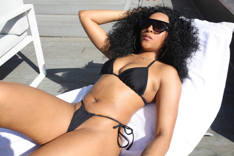 Model on sun lounger relaxing wearing black bikini