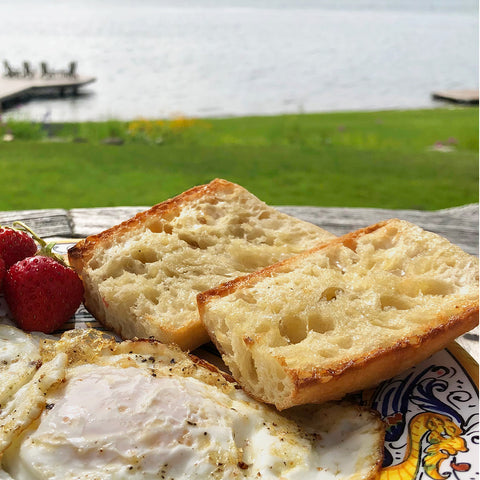 Breakfast of ciabatta demi baguette with eggs and strawberries in beautiful waterfront setting