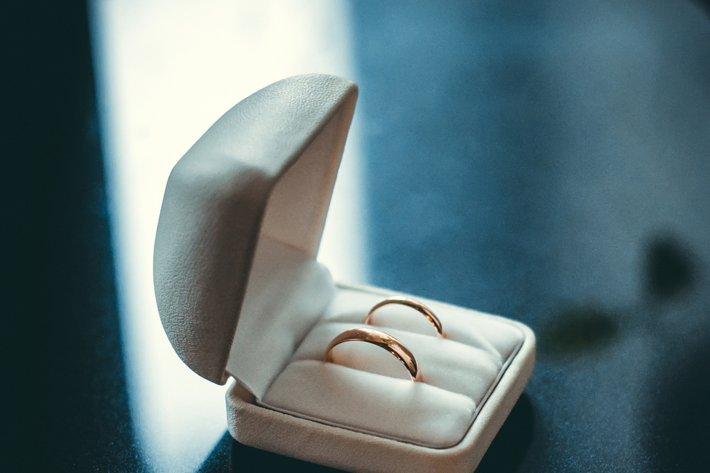 Two wedding bands sit inside an open bridal rings box. 