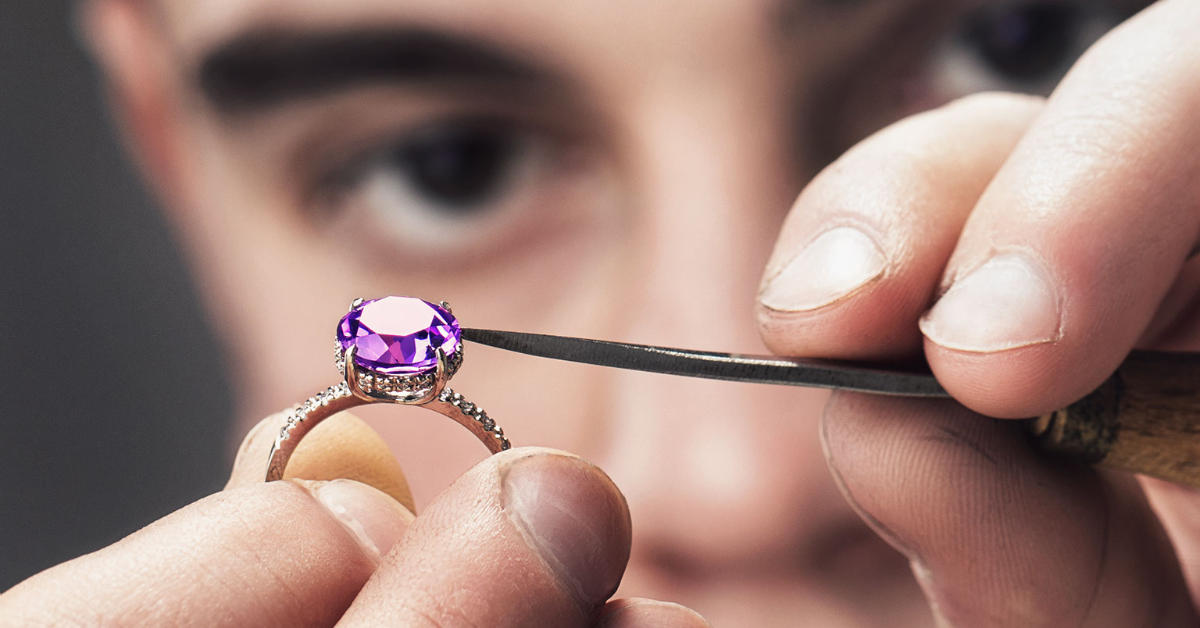 A master jeweler works on installing the center stone in an engagement ring that's part of a bridal rings set. 