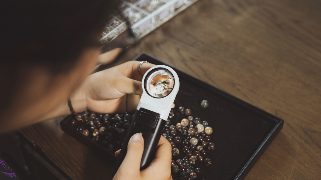 A jewelry appraiser looks at precious gemstones under a magnifying glass.