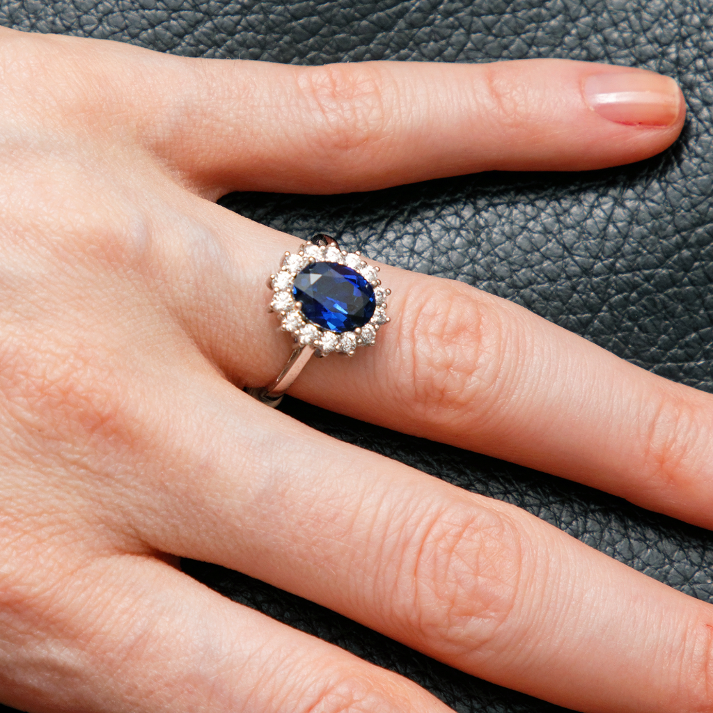 A sapphire and diamond ring on a woman's hand.