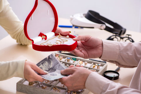 A customer pays an Albuquerque jeweler for a repaired necklace and earrings in a box.