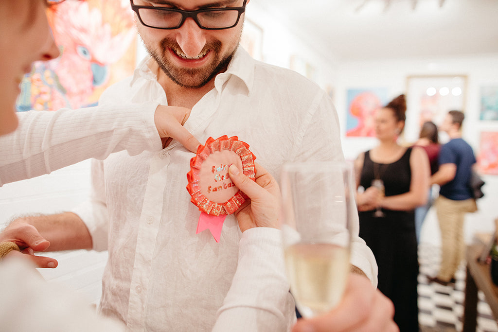 Pinning pink badge for Alykat gallery Fairy Floss Fantasy group exhibition opening night.