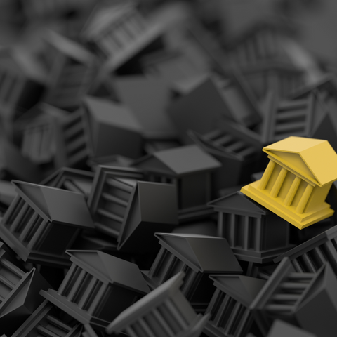 A single golden toy building in a pile of black toy buildings