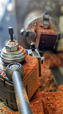 Close-up of a clarinet barrel being crafted on a lathe at ZM Concept, with wood shavings spiraling away as the barrel takes shape