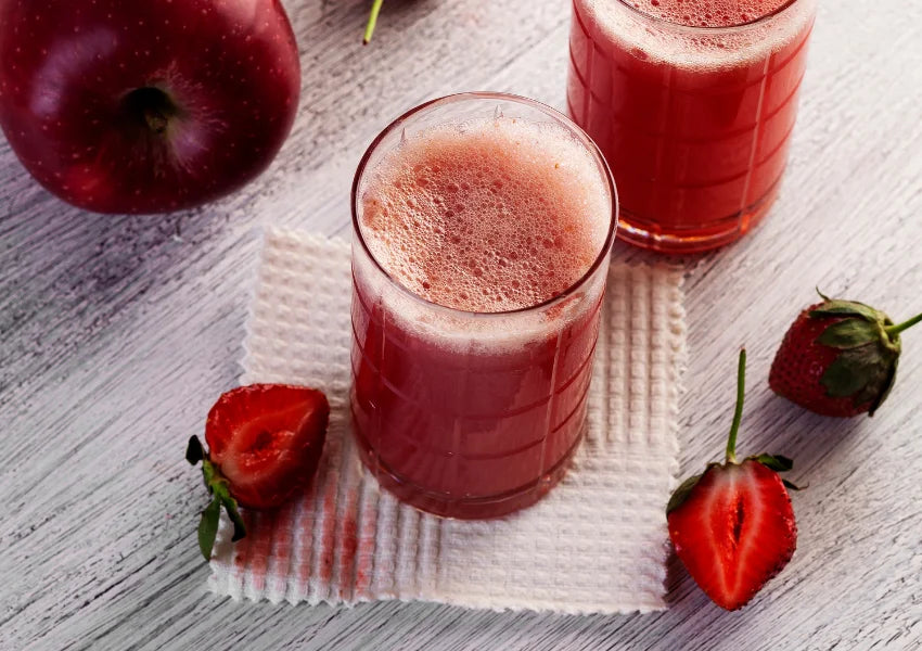 Whole apple, whole red and sliced strawberries and apple juice on wooden table