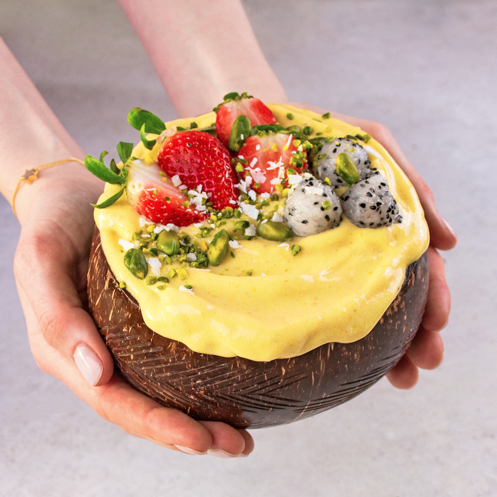 Gelbe Smoothie Bowl mit Früchten und Pistazien