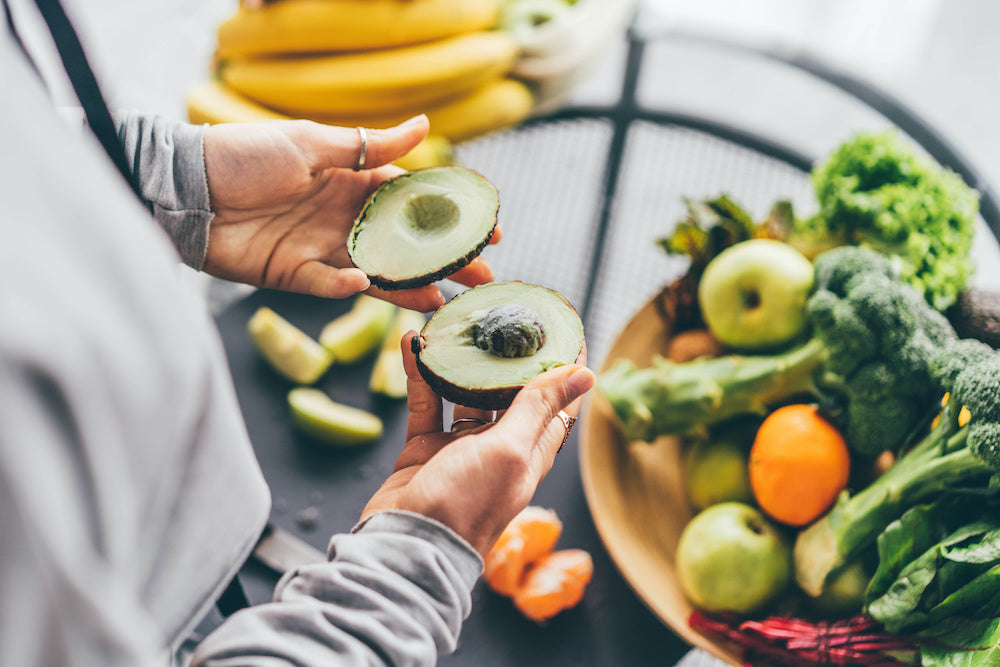 Frau hält halbierte Avocado