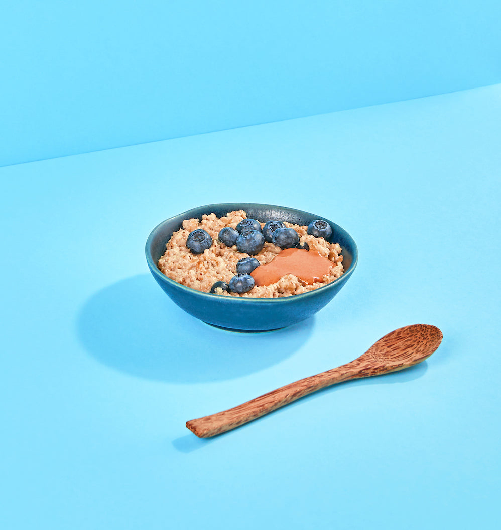 Blaue Schale mit Porridge und Blaubeeren auf blauem Hintergrund