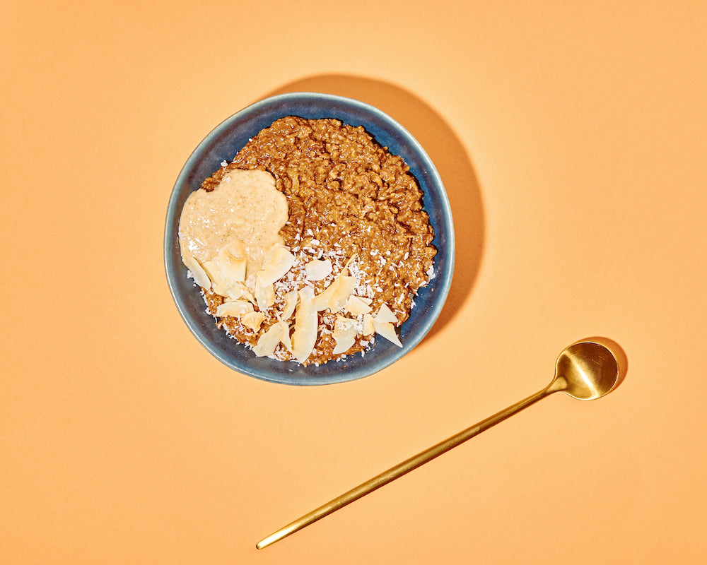 Kokos Porridge in Schale auf orangem Hintergrund