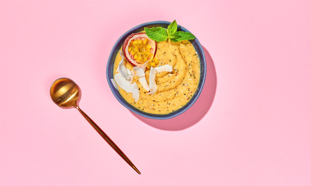 Smoothie Bowl mit Mango auf rosa Hintergrund