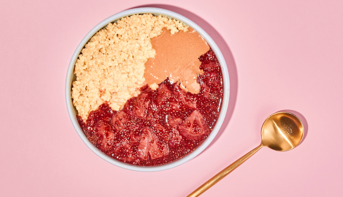 Hirse Porridge mit Erdbeerkompott auf rosa Hintergrund