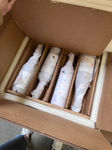 Four Joyus Non-Alcoholic Wine bottles wrapped in tissue paper and packed inside of a corrugated box lined with environmentally friendly insulation