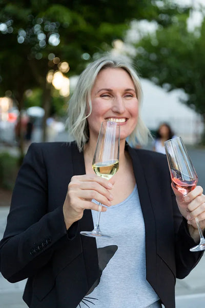 Joyus founder Jessica Selander holding two champagne flutes of Jøyus non-alcoholic wine