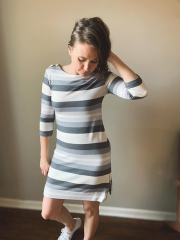 a girl wearing a gray striped dress looking down.