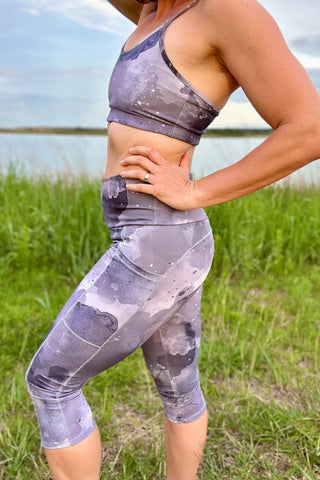 A girl wearing gray clouded workout leggings and sports bra.