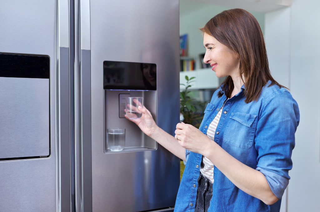 a woman is getting water from a refrigerator water dispenser