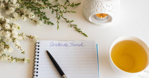 gratitude journal with tea, a candle, and flowers - splashpad self care
