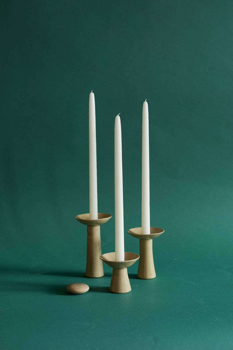 Three ceramic candlesticks by Cara Guthrie. Shot against a deep green backdrop at Bard Scotland.