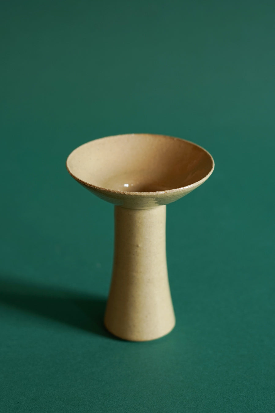 The medium size of candlestick by Cara Guthrie in the colour Clay.