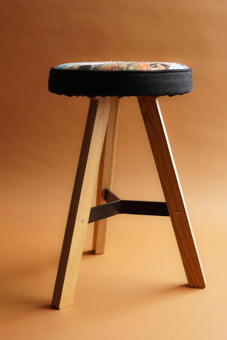 Side view of the Embroidered Commonwealth Stool from Laura Lees. Displaying the wooden frame by Uncommon Projects.