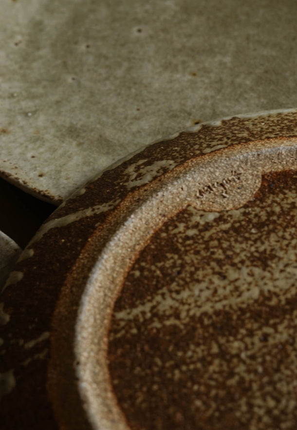 Reverse of Ingot Objects ash glazed side plate. Deep mottled tones and the makers backstamp can be seen.