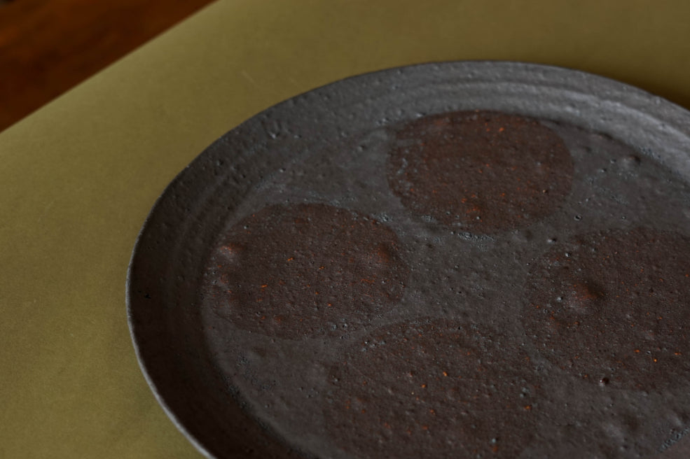 Side angle of the Black Platter from Ingot Objects. Four circles of a ghostly pink iron resist markings can be seen on the plates surface.