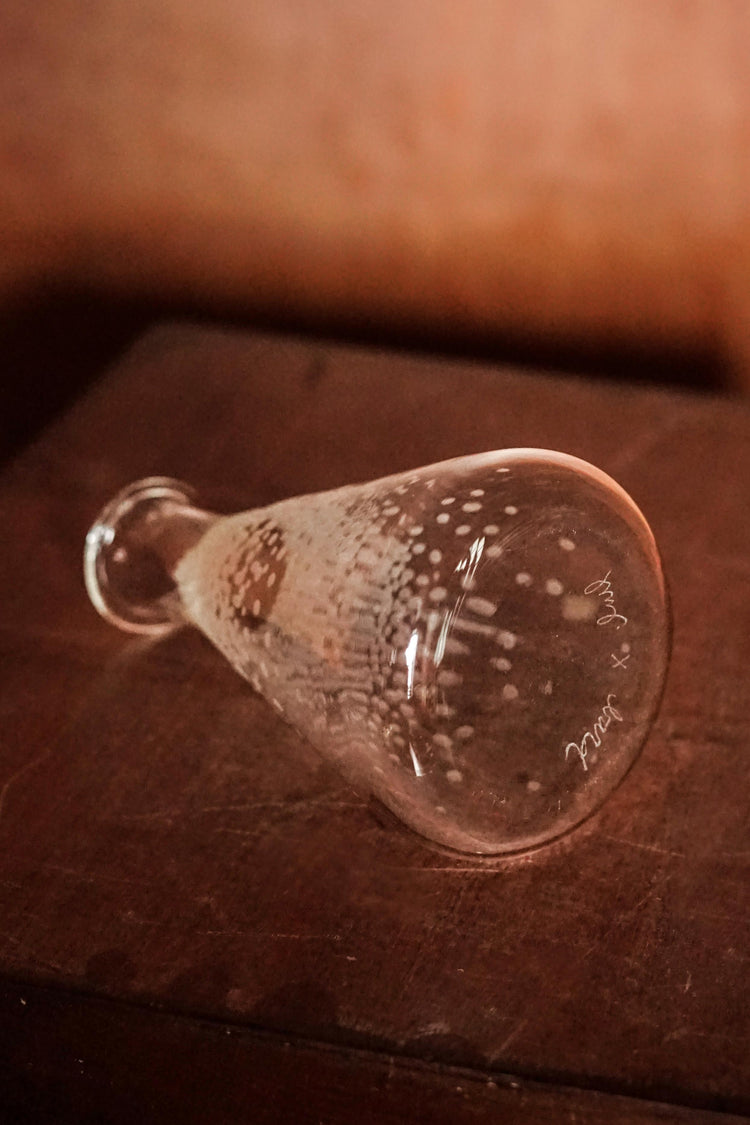  The Medium Conical Beaker, part of Second Lives by Juli Bolaños-Durman. The Beaker is tilted on its side so we can see the bottom of the piece and Juli's makers mark.