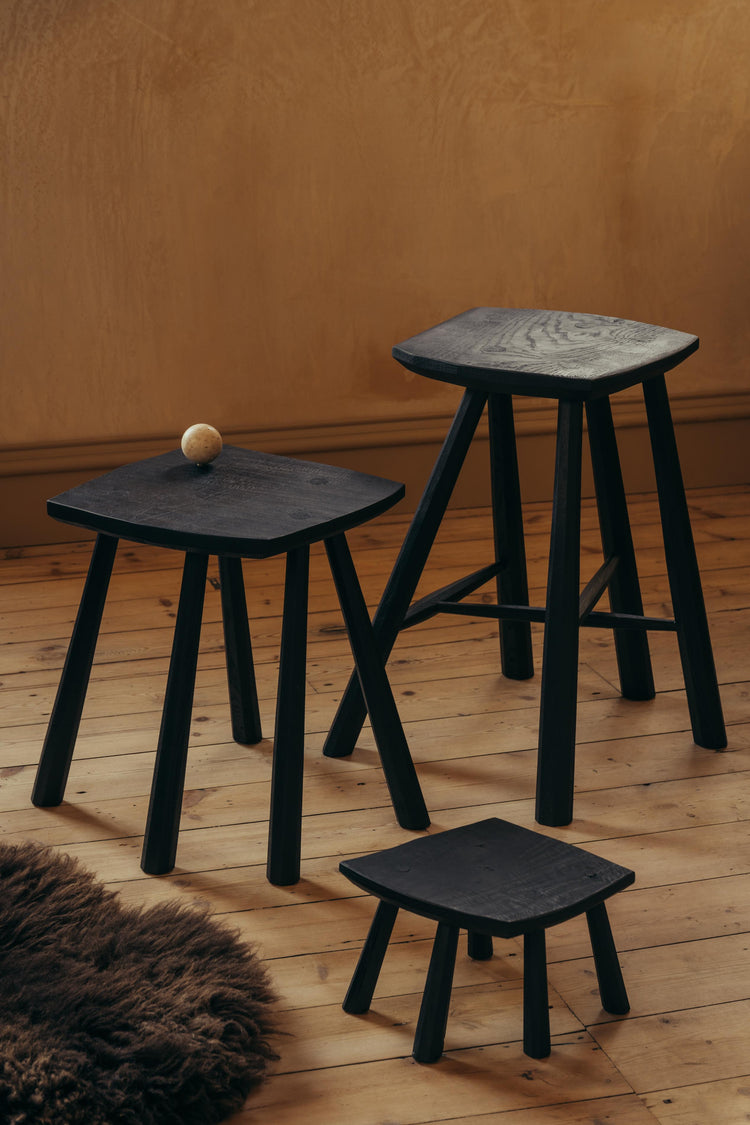 The tallest of the three stools is the 'High Stool', the medium is the 'Stool', and the smallest the 'Crawlie'. ALT = Black House Stools by Sheahan Made. A family of stools handmade from Scottish ash, stained with Indian ink and finished with beeswax. 