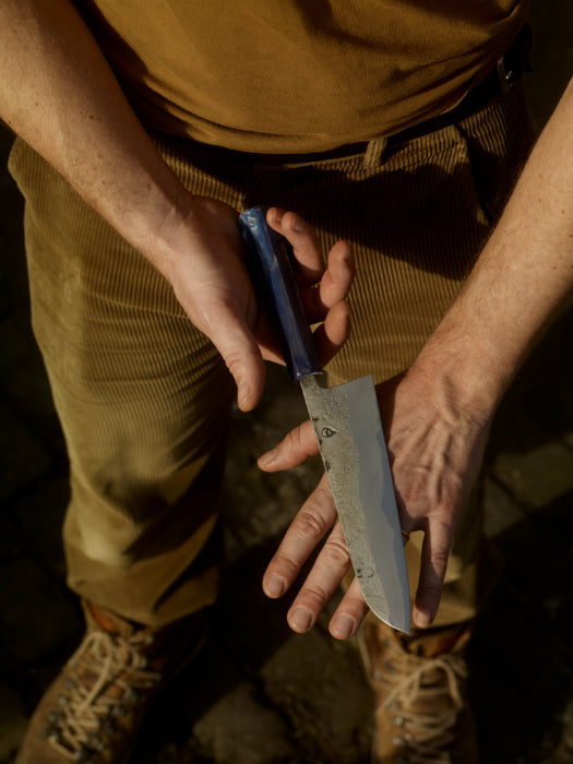 6" chef knife with a recycled plastic blue handle in James' palm.